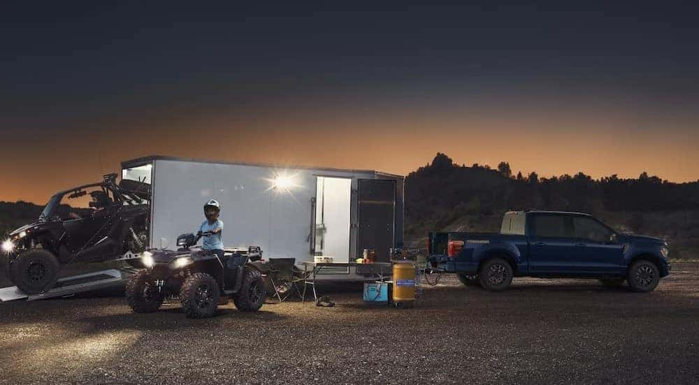 A blue 2025 Ford F-150 Tremor is shown parked while towing a trailer.