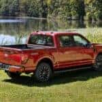 A red 2024 Ford F-150 Lariat is shown from the rear at an angle.