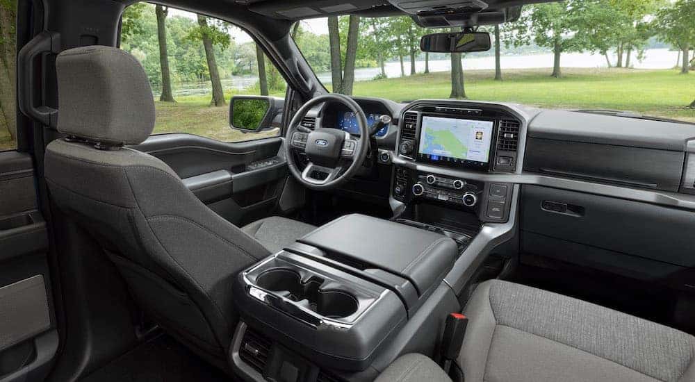 The grey interior of a 2024 Ford F-150 for sale near Westcliffe is shown from the back seat.