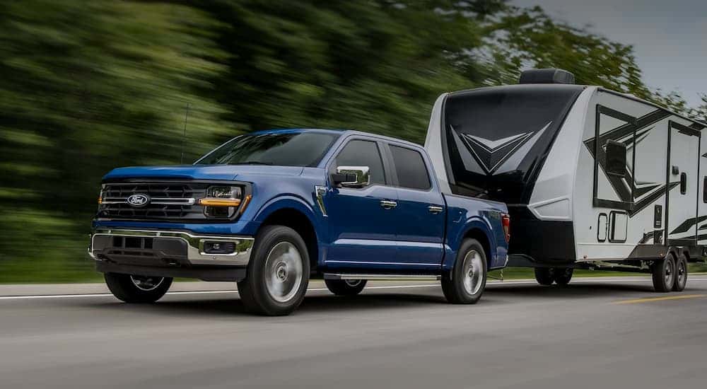 A blue 2025 Ford F-150 towing a trailer.