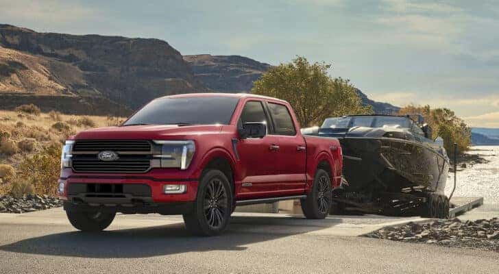 A red 2025 Ford F-150 Platinum backing a boat into a body of water.
