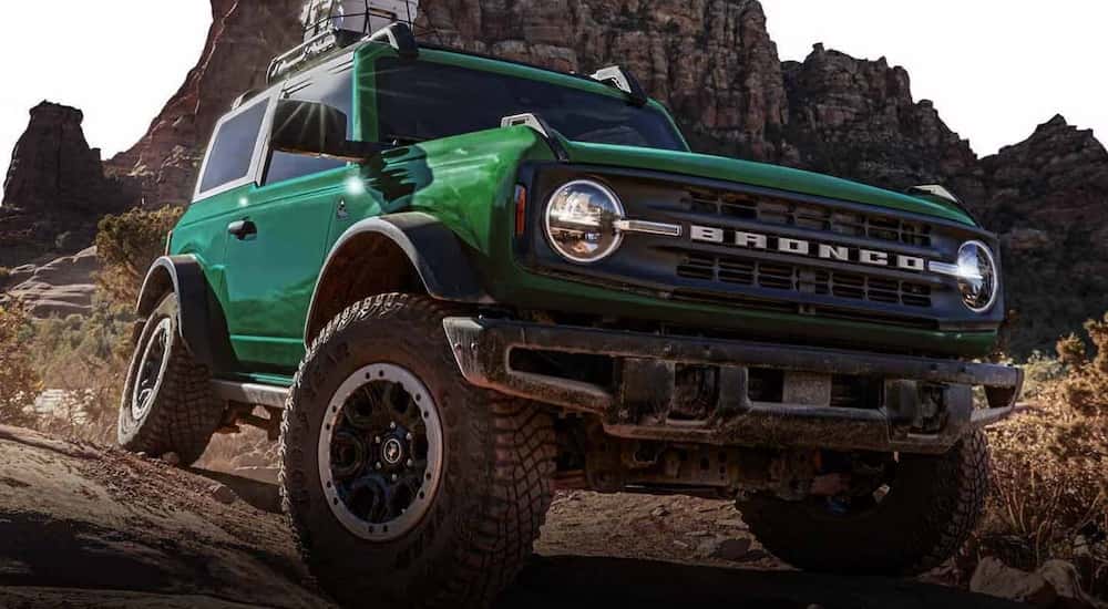 A green 2025 Ford Bronco driving down a dirt hill.