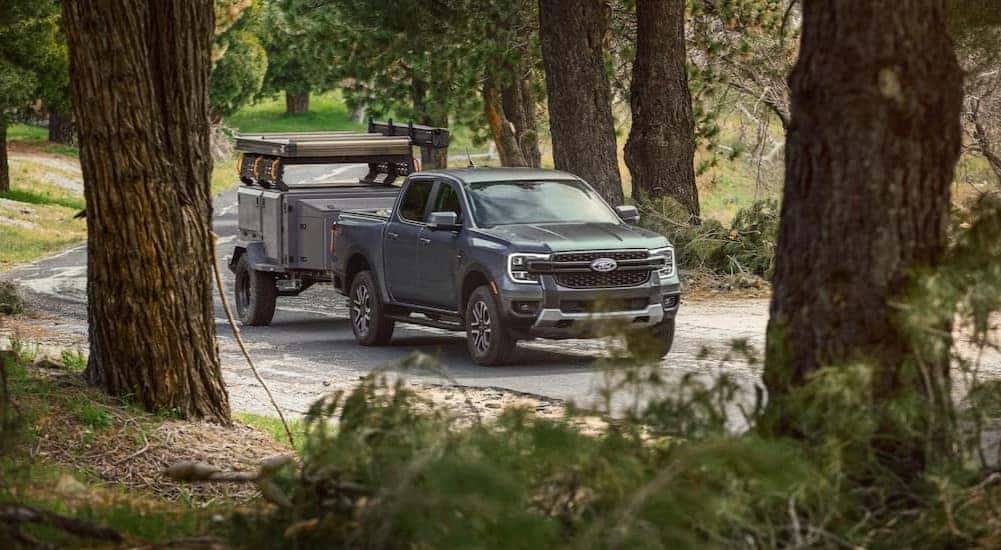 A gray 2025 Ford Ranger is shown towing a trailer on a backroad.