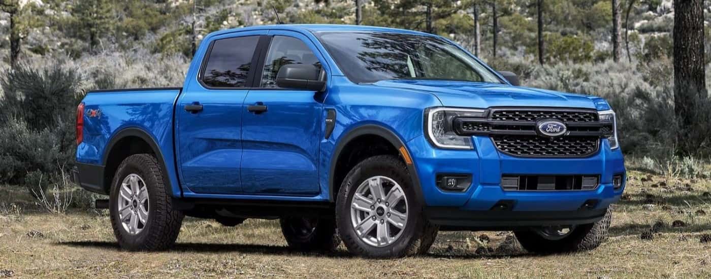 A blue 2024 Ford Ranger STX parked off-road in a forest.