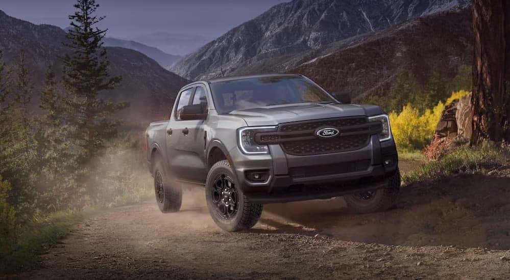 A gray 2025 Ford Ranger for sale is shown driving on a dirt path
