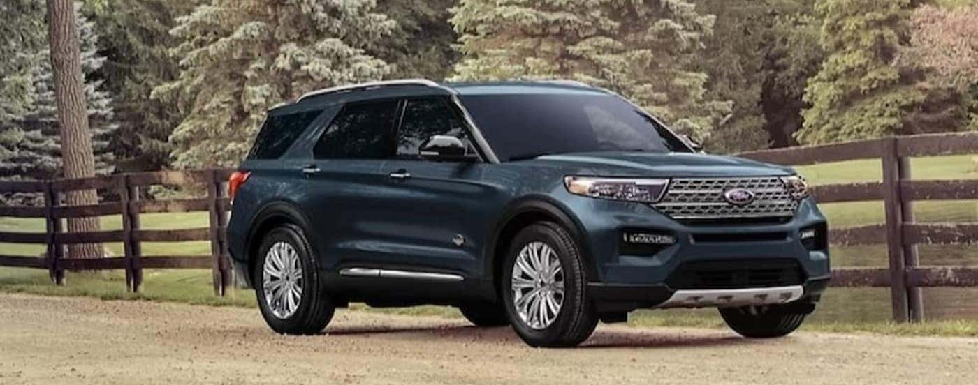 A green 2024 Ford Explorer King Ranch parked near a wooden fence.