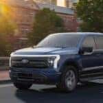 A blue 2025 Ford F-150 Lightning driving to a Ford dealer near Florence.