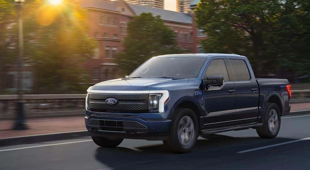 A blue 2025 Ford F-150 Lightning driving to a Ford dealer near Florence.
