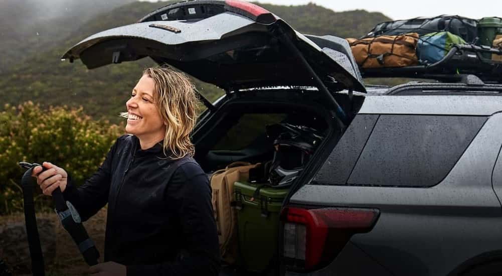 A person standing at the rear of a gray 2026 Ford Explorer.