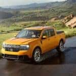 An orange 2022 Ford Maverick is shown driving through the hilly countryside after visiting the Salida Ford dealership.