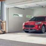 A red 2020 Ford Escape Plug-In Hybrid is shown charging in a garage after leaving a Certified Pre-Owned Ford dealership.