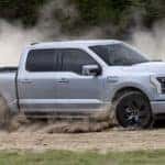 A silver 2022 Ford F-150 Lightning Lariat is shown from the side on a dirt course after leaving a Gunnison Ford dealer.