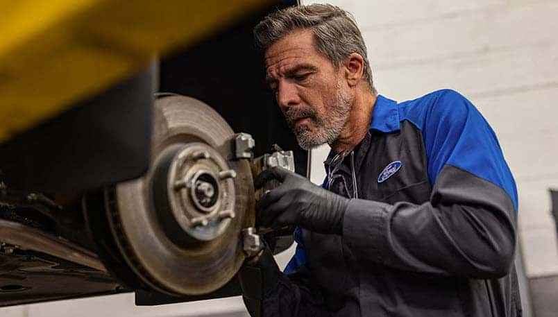 Ford technician performing brake inspection during fall service at Greg Hubler Ford in Muncie Indiana