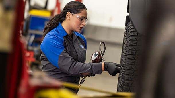 Ford technician inspecting tire pressure during seasonal maintenance at Greg Hubler Ford