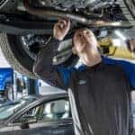 Ford technician performing undercar inspection at certified service center in Muncie