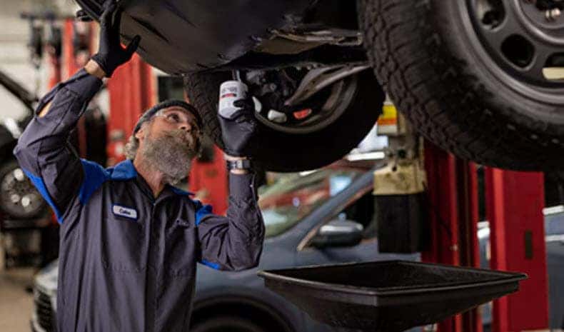 Certified Ford service expert checking vehicle components during winter maintenance