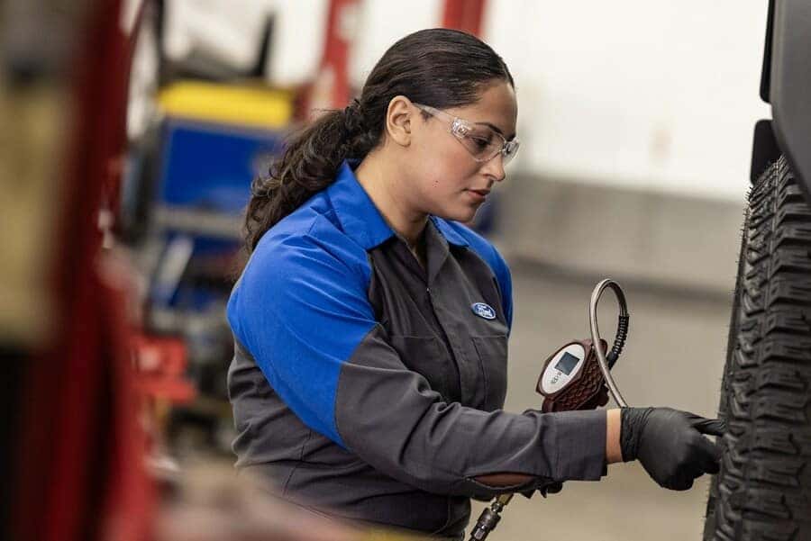 Ford service technician checking tire pressure and inspecting winter tires at Greg Hubler Ford in Muncie IN