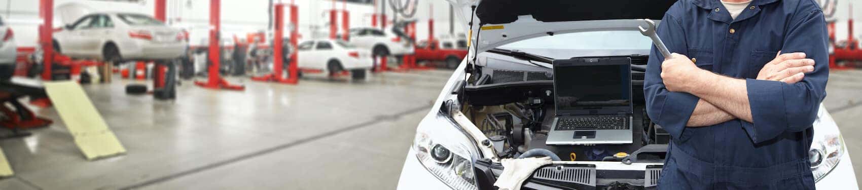 Mechanic standing in front of car about to perform vehicle inspection
