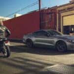 Gray Ford Mustang Sports Car Motorcycle Man Buildings
