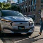 Gray Ford Mustang Mach-E EV SUV Buildings Street Person