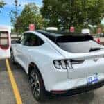 White Ford Mustang Mach-E SUV Tesla Charging Station