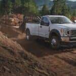 White Ford Super Duty Pickup Truck Brown Mud Tree Logs