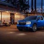 blue Ford Maverick pickup three people outside patio with lights