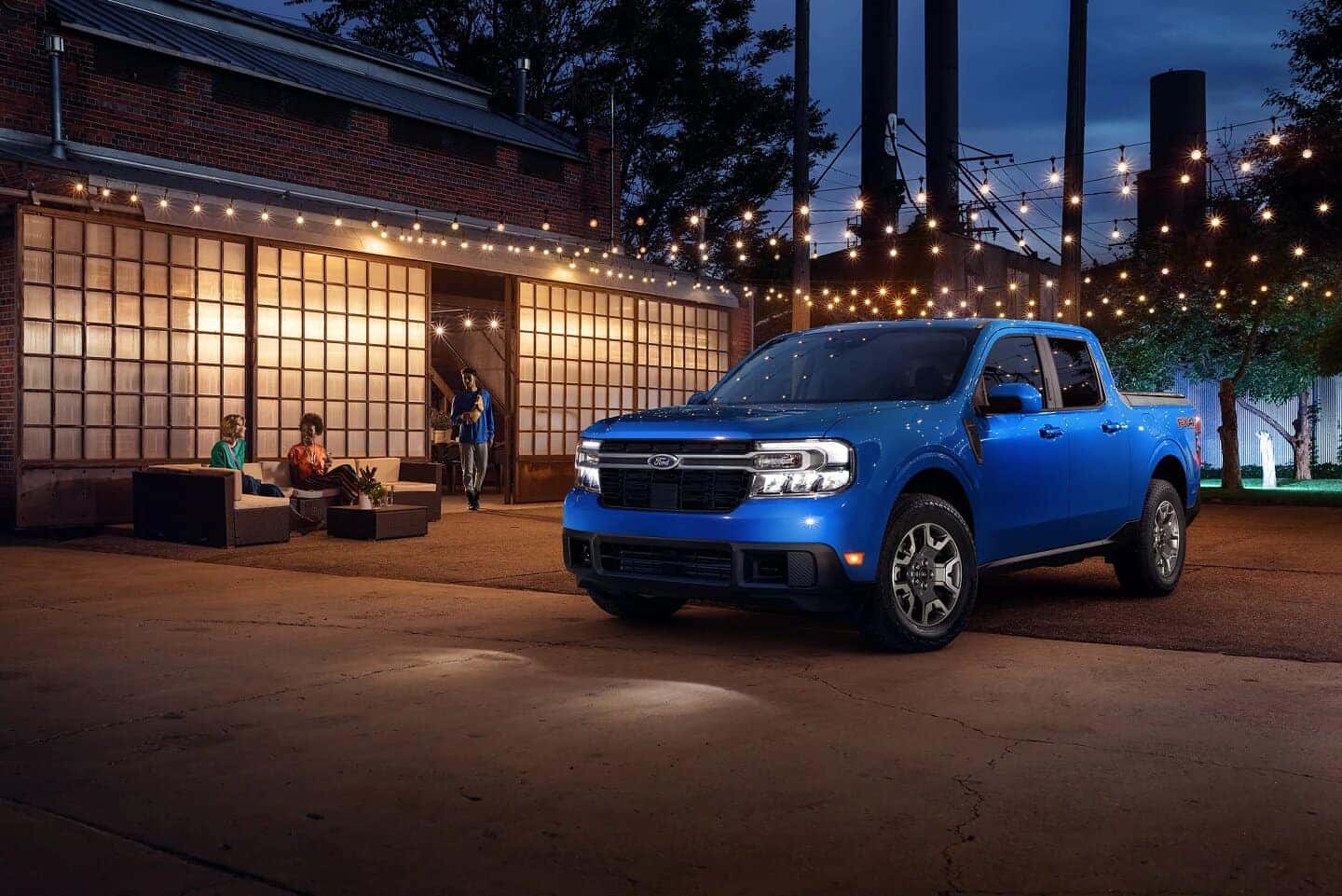blue Ford Maverick pickup three people outside patio with lights