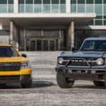 Yellow Ford Maverick pickup blue Ford Bronco outside building