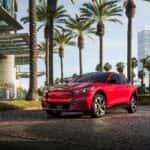 Red Ford Mustang Mach-E SUV Trees Buildings