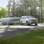 White Ford Expedition SUV White Boat Trees Gras Water