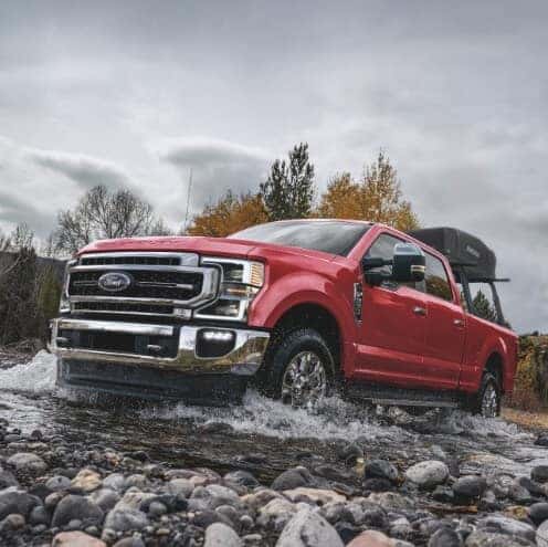 Red Ford Super Duty Pickup Truck Rocks Trees Water