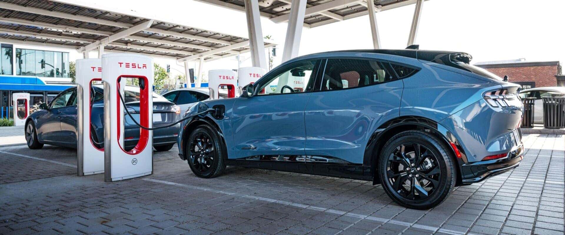 Blue Ford Mustang Mach-E EV SUV Tesla Charging Station
