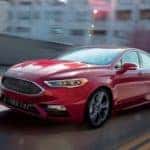A red Ford Fusion, acquired from Ford Lease Deals, races down a city street