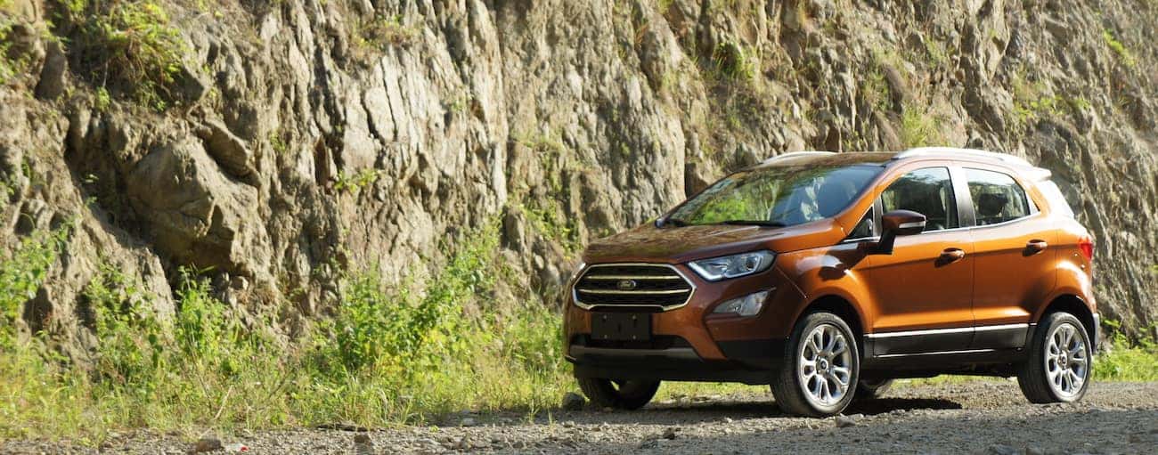 A bright orange 2019 Ford EcoSport parked next to a rock ledge
