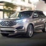 A silver 2019 Ford Edge travels a city city street in Ohio at night