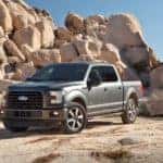 A gray 2015 Ford F150 in front of a rock pile