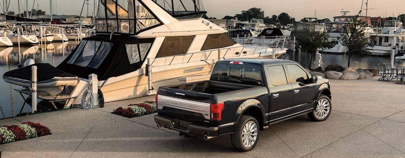 Rear of a black 2019 Ford F-150 parked next to a large yacht 