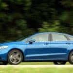 A blue 2017 Ford Fusion is driving in front of greenery and was purchased as a Ford Certified Pre Owned Vehicle in Cincinnati, OH.