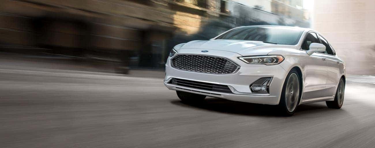 A white 2020 Ford Fusion is driving quickly down a road in Cincinnati, OH.