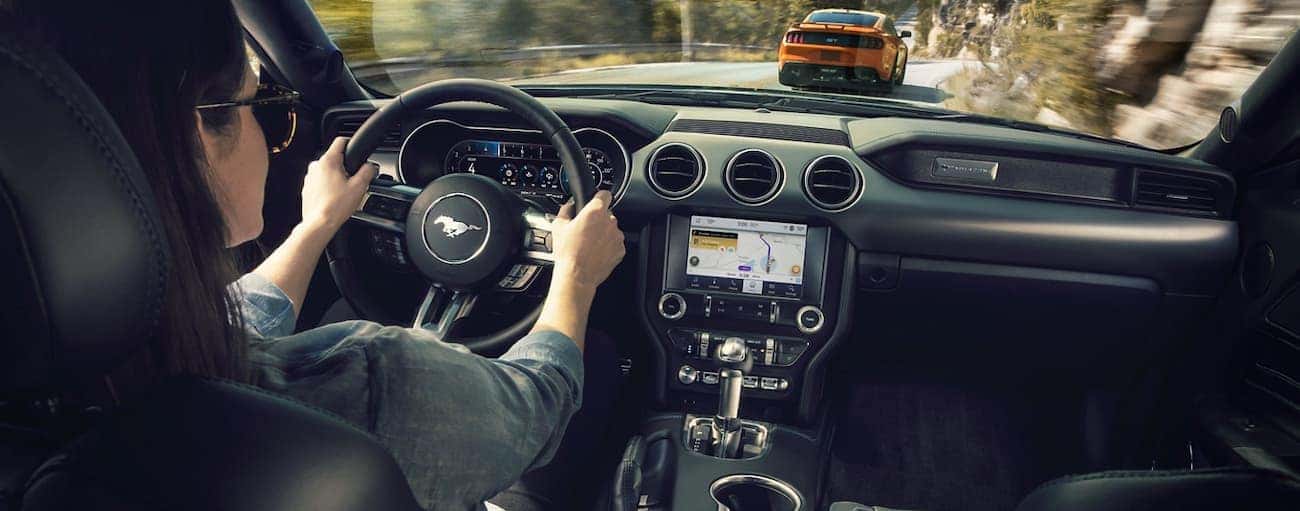 A woman is shown driving form inside her 2020 Ford Mustang.