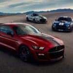 A red, a silver, and a blue 2020 Ford Mustang Shelby GT 500, which are popular Ford cars for sale, are parked on a racetrack.