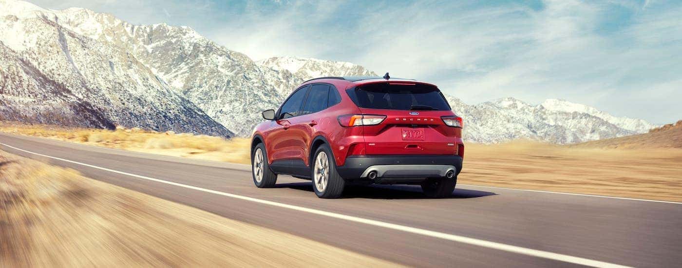 A red 2020 Ford Escape driving towards a snow-covered mountain.