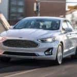 A white 2020 Ford Fusion is driving on a city street after leaving a Cincinnati car dealer.