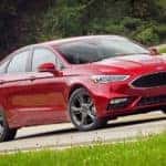 A red 2017 Ford Certified Pre-Owned Fusion is driving on a winding road.