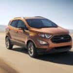 One of the popular Ford SUVs in Cincinnati, OH, an orange 2020 Ford EcoSport is driving on an empty road.