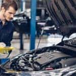 A mechanic is holding a yellow clipboard next to a car at a service center for Ford in Cincinnati, OH.
