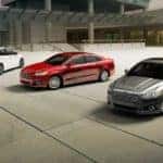 A white, a red, and a grey 2015 used Ford Fusion are shown parked in a courtyard.