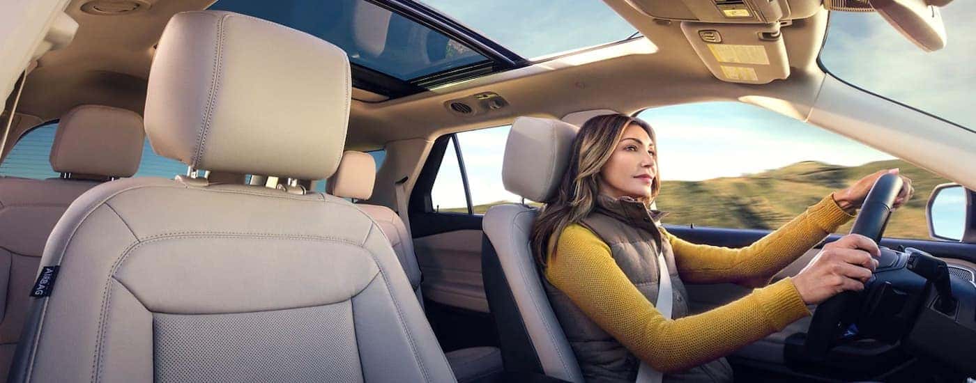 A 2021 Ford Explorer Hybrid is shown with a woman driving in the tan interior.