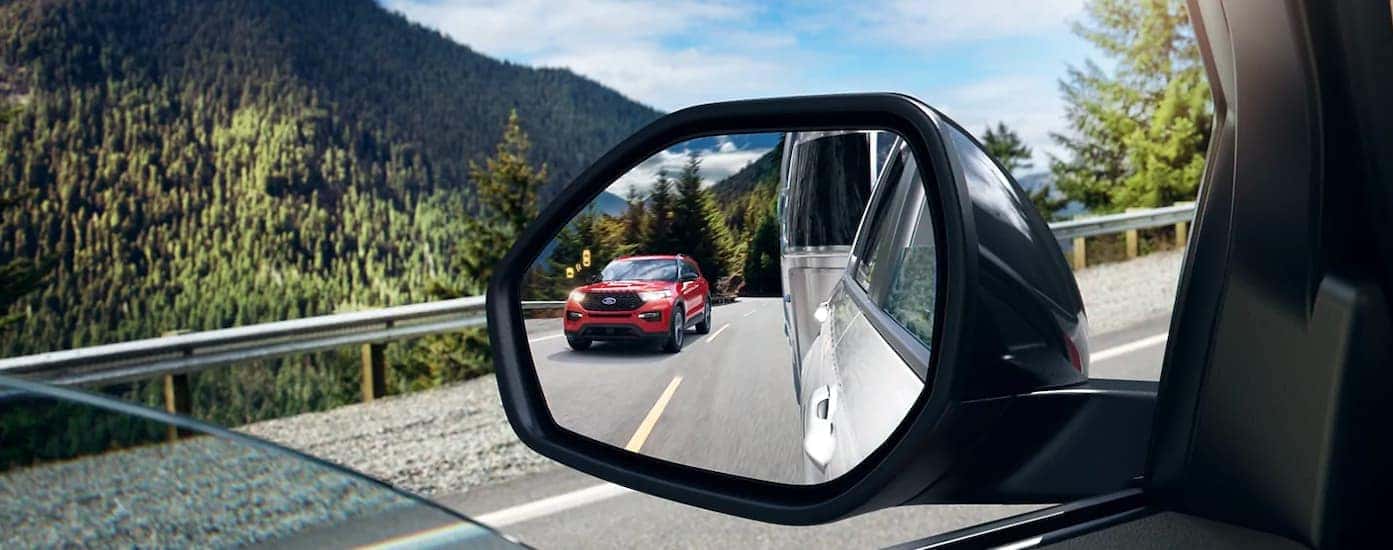 A close up is shown of the mirror and blind spot monitoring icon on a 2021 Ford Explorer Hybrid.